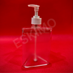A transparent, triangular soap dispenser with a white pump head against a red background.