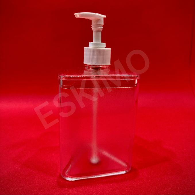 A transparent, triangular soap dispenser with a white pump head against a red background.